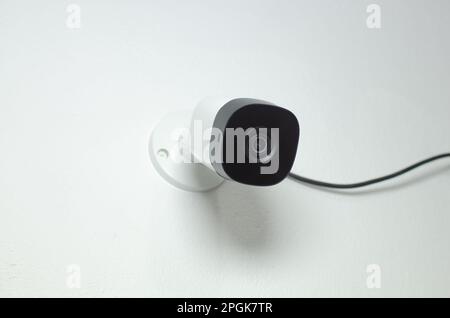 A close-up of a security camera mounted on a wall in a modern office, ready to be used Stock Photo