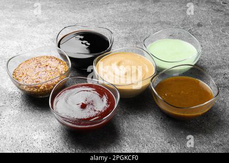 Many bowls with different sauces on grey table Stock Photo