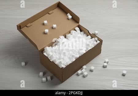 Cardboard box and styrofoam cubes on wooden floor Stock Photo