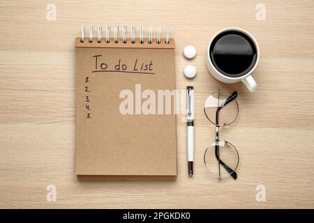 Flat lay composition with unfilled To Do list, cup of coffee and glasses on wooden table Stock Photo