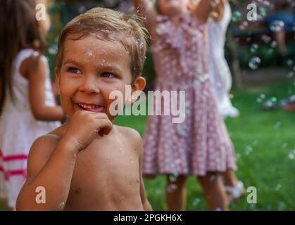 Happy birthday. A 3-4 year old child is having fun in a park with balls and bubbles. Soft focus Stock Photo
