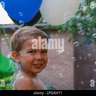 Happy birthday. A 3-4 year old child is having fun in a park with balls and bubbles. Soft focus Stock Photo