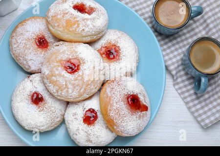 Delicious jam donuts served with coffee on white wooden table, flat lay Stock Photo