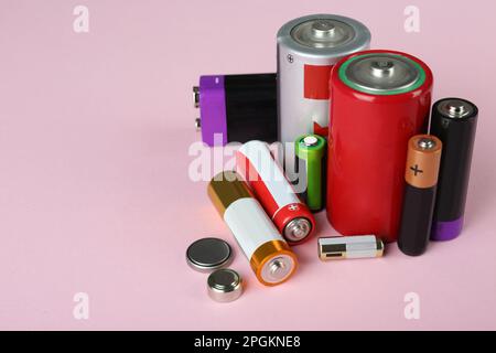 Different types of batteries on pink background, space for text Stock Photo