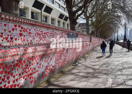 London, UK. 23rd March 2023. People walk past the National Covid Memorial Wall on the third anniversary of the first national coronavirus lockdown. Thousands of red hearts have been painted on the wall outside St Thomas' Hospital, one for each life lost to Covid-19. Credit: Vuk Valcic/Alamy Live News Stock Photo