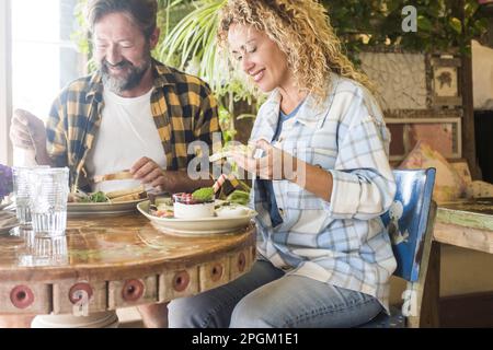Man and woman enjoying lunch together sitting at the table in a cafe restaurant smiling and talking with happiness. Dating people eating brunch in bar Stock Photo