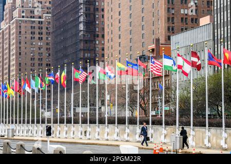New York, USA. 23rd Mar, 2023. Delegates walk past national flags at the entrance of the United Nations headquarters during the UN 2023 Water Conference. Delegates from 196 countries and international organizations are addressing the 3-day United Nations Conference on the Midterm Comprehensive Review of the Implementation of the Objectives of the International Decade for Action “Water for Sustainable Development”, 2018-2028. Credit: Enrique Shore/Alamy Live News Stock Photo