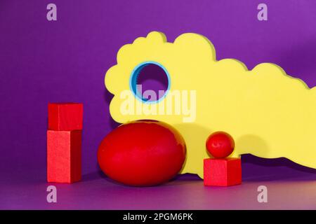 red Easter egg on the purple background, various geometric shapes around that Stock Photo