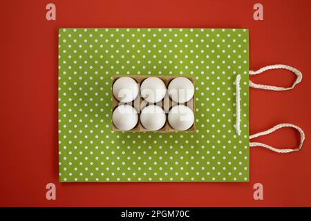 Easter eggs on decorative shopping bag. Rabbit ears made of rope. Vintage style. Creative concept. Red background. Flat lay. Stock Photo