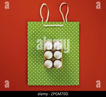 Easter eggs on decorative shopping bag. Rabbit ears made of rope. Vintage style. Creative concept. Red background. Flat lay. Stock Photo