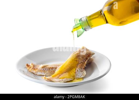 Cod fillet in white dish with extra virgin olive oil poured from bottle with drip cap. Isolated on white with clipping path included Stock Photo