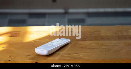 White remote control placed on wooden floor Stock Photo
