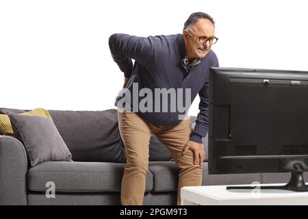 Mature man with back pain getting up from a sofa in front of tv isolated on white background Stock Photo