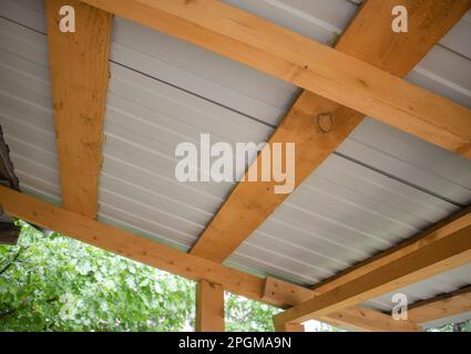 Close-up of wooden roof rafters with metal corrugated board, bottom view. Stock Photo