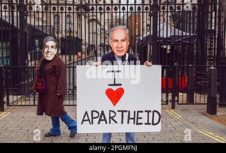 London, UK. 23rd Mar, 2023. Amnesty International UK activists wearing Benjamin Netanyahu and Rishi Sunak masks stand outside Downing Street with an 'I Love Apartheid' placard during a protest as the Israeli Prime Minister visits the UK. Credit: SOPA Images Limited/Alamy Live News Stock Photo
