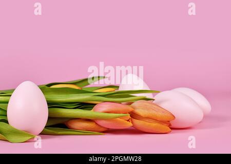 Tulip spring flowers and pink Easter eggs on pink background with copy space Stock Photo