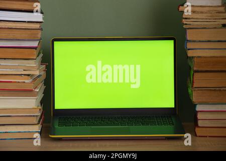 laptop green screen and a stack of books on the table Stock Photo