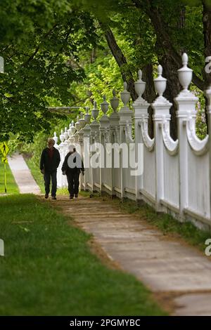 Couple walking past decorative fence surrounding the old first Congregational Church in Bennington Vermont Stock Photo