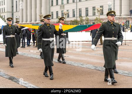 Vilnius  Lithuania - March 11 2023: Soldiers in official uniforms marching through the streets of the capital Vilnius, Lithuania with a big flag Stock Photo