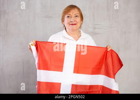 Smiling elderly woman waving flag of Denmark in studio Stock Photo