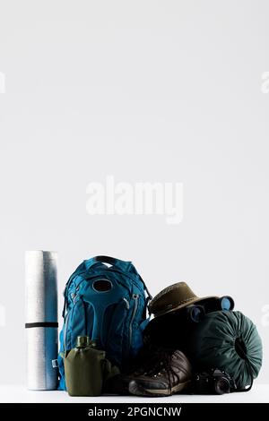 Close up of blue backpack, mat, trekking sticks and sleeping bag on white background with copy space Stock Photo