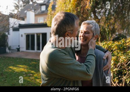 Happy affectionate senior couple hugging in garden Stock Photo