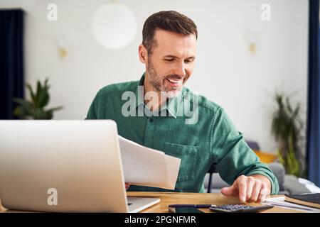 Contented man doing paperwork calculating finaces Stock Photo