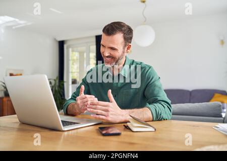 Cheerful man having video call sitting at desk at home Stock Photo