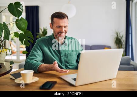 Man having video call sitting at desk using laptop Stock Photo