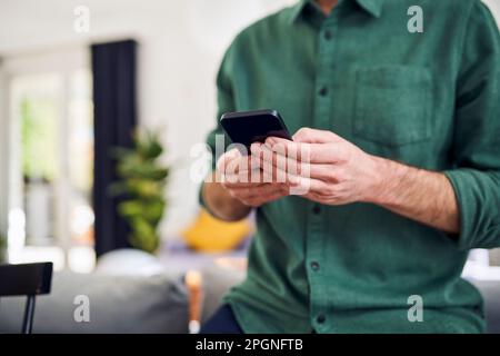 Man using smartphone leaning on couch Stock Photo
