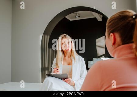 Psychologist taking notes in counseling session at clinic Stock Photo