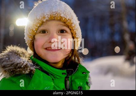 Cute boy wearing knit hat covered in snow at night Stock Photo