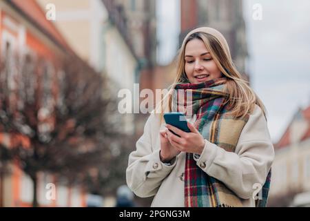 Smiling young woman using mobile phone Stock Photo