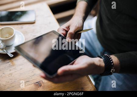 Hands of man using tablet PC on table in cafe Stock Photo