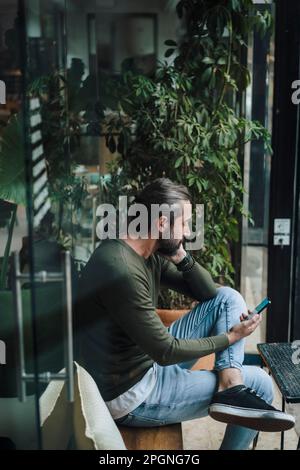 Mature man using smart phone in cafe Stock Photo