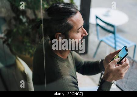 Man using smart phone sitting in cafe Stock Photo
