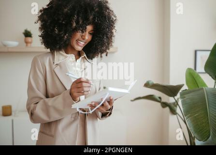 Happy young businesswoman writing down notes in office Stock Photo