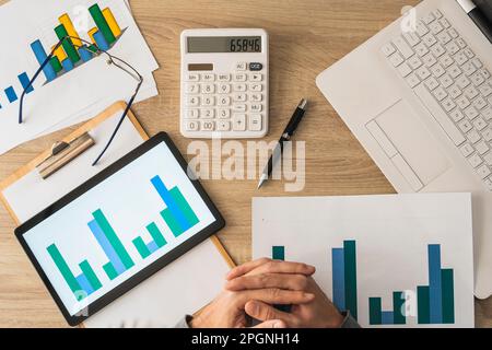 Hands of businessman with calculator and graphs on table Stock Photo