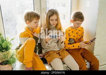 Happy boy with siblings using smart phone at home Stock Photo
