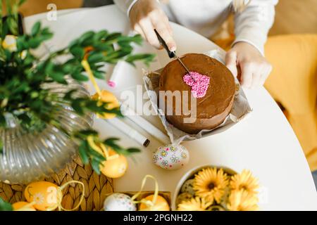 Hands of girl cutting Easter cake on table at home Stock Photo