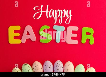 Happy Easter text with red background decorated with chocolate eggs. Can be used to say Happy Easter to anyone. Stock Photo