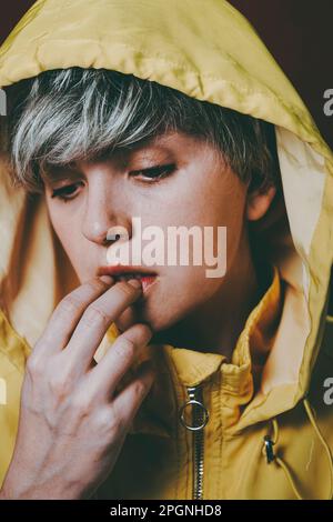 Thoughtful woman wearing yellow hooded jacket Stock Photo