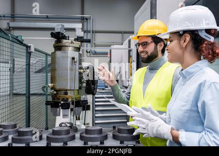 Happy engineer holding blueprint with colleague in office Stock Photo