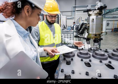 Engineer and colleague checking blueprint in factory Stock Photo
