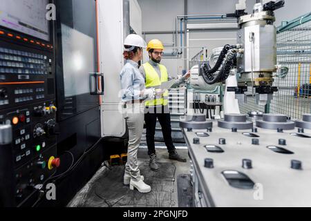 Young engineer and colleague having discussion in factory Stock Photo