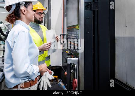 Smiling engineers looking at control panel screen in factory Stock Photo