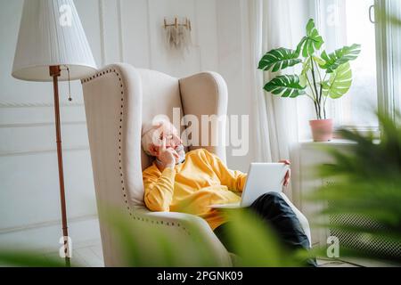 Thoughtful freelancer with laptop sitting on armchair Stock Photo