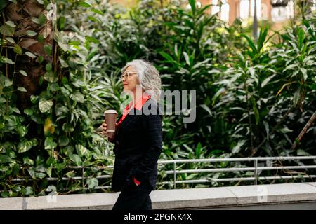 Businesswoman with disposable cup walking in garden Stock Photo