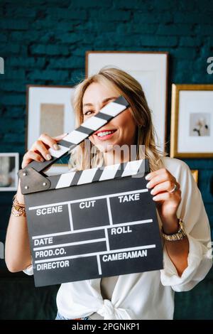 Smiling actress holding clapboard on film set Stock Photo