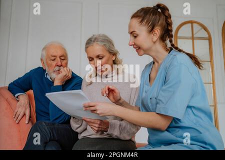 Senior patients reading medical reports by nurse at home Stock Photo